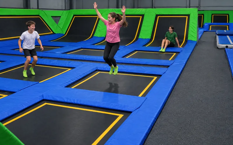 Nastolatki skaczą na trampolinach w Jumpout, każde na swoim polu (obraz wygenerowany przez AI)
