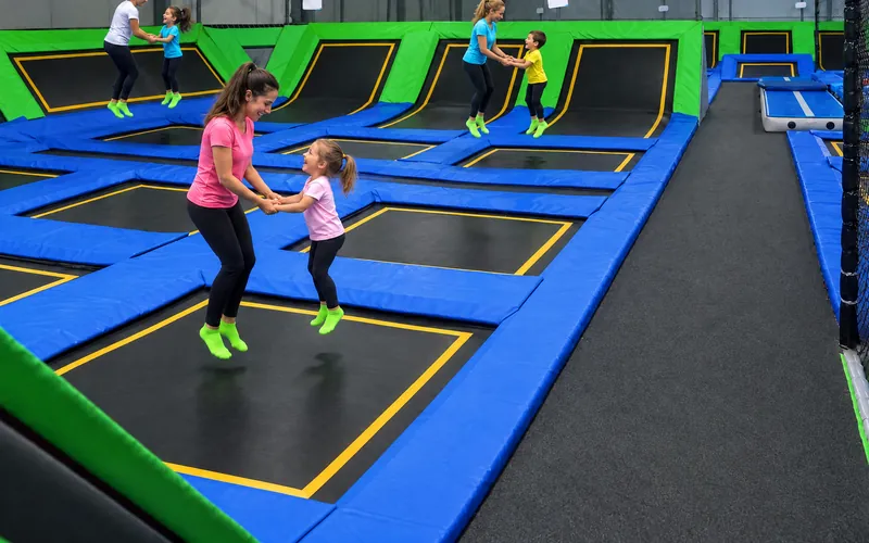 Przedszkolaki skaczą z opiekunkami, każda para na swojej trampolinie (obraz wygenerowany przez AI)