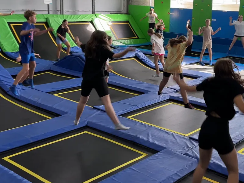 Uczniowie skaczą na trampolinach w czasie wyjazdu klasy, widok od tyłu