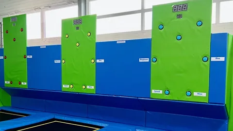 Zielone panele interaktywnej ściany z licznikami punktów nad trampolinami