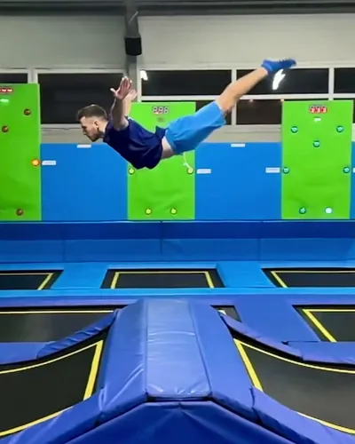 Instruktor w locie nad trampolinami przy ścianach interaktywnych w Jumpout