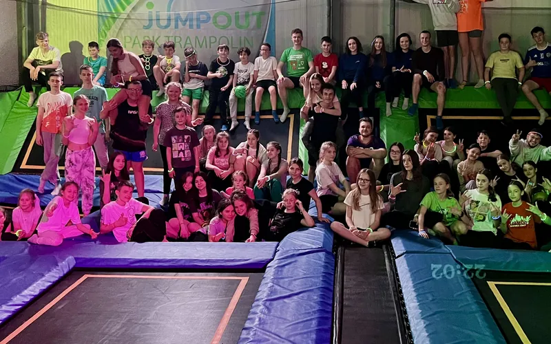 Uczestnicy nocnego skakania w Jumpout pozują na trampolinach w neonowym świetle