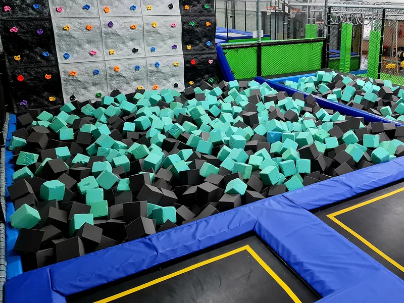 Basen z gąbkami pod ścianką boulderową w Jumpout, przed nim pola trampolin z żółtym obrysem